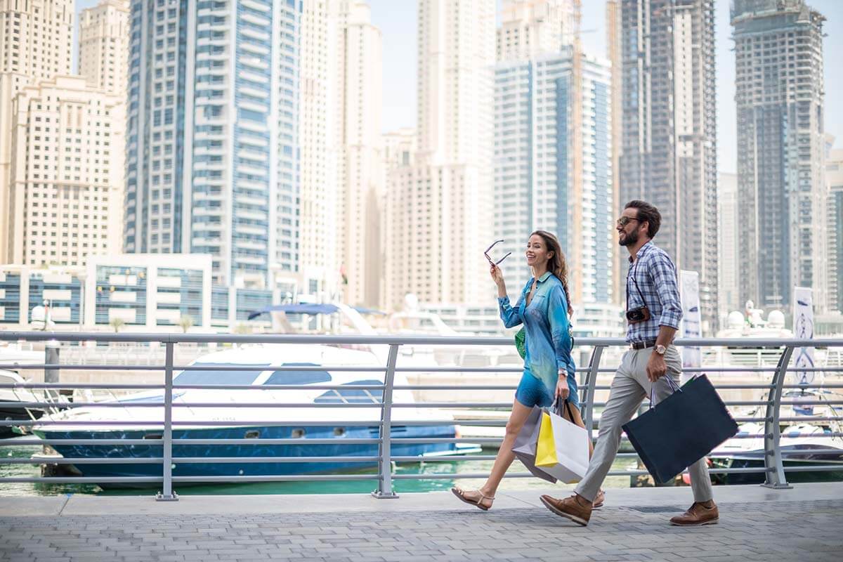 Couple strolling on waterfront carrying shopping bags, Dubai, United Arab Emirates