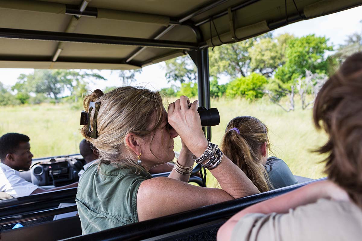 Tourist using binoculars in a safari vehicle in Masai Mara